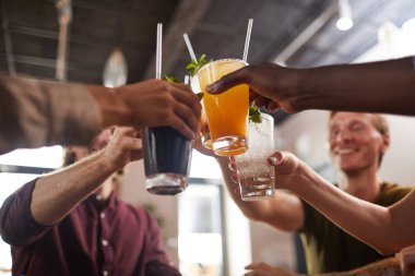 Arkadaşların kafeteryada oturup soğuk içeceklerin keyfini çıkarırken bardaklarını tokuşturdukları alçak açı.