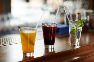 Bar tezgahında üç renkli içecek, ferahlatıcı kokteyller ve mojito bardakları, kopyalama alanı.