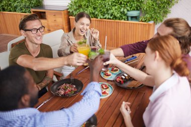 Kadeh kaldıran ve kadehleri tokuşturan çağdaş insanlardan oluşan bir gruba yüksek açılı bir bakış açısı.