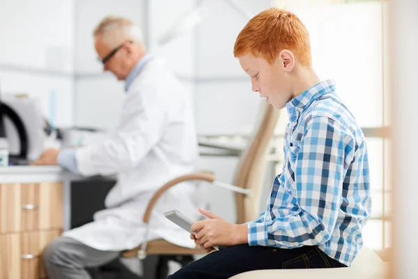 Doktor Odasındaki Bekleme Odasında Dijital Tablet Kullanan Kızıl Saçlı Gencin — Stok fotoğraf