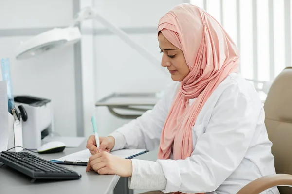 히잡을 여성의 초상화가 클리닉에서 간호사로 일하고 환자를 책상에 공간을 만들었습니다 — 스톡 사진