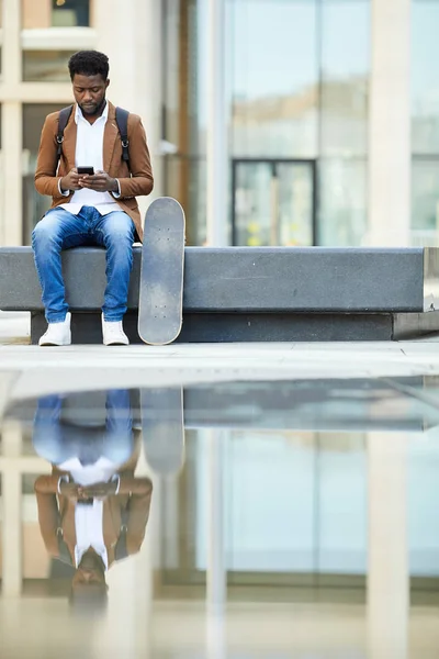 Retrato Comprimento Total Jovem Afro Americano Usando Smartphone Enquanto Sentado — Fotografia de Stock