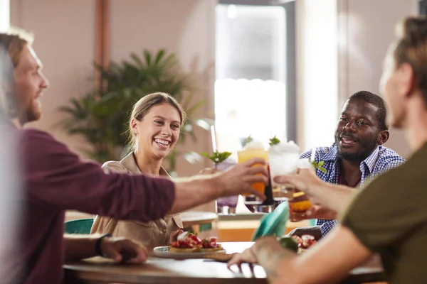 Grupo Multiétnico Amigos Tintineando Vasos Mientras Están Sentados Mesa Cafetería — Foto de Stock