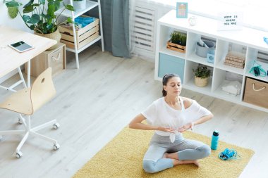 Modern genç bayana geniş açılı bakış açısı evde meditasyon yaparken nefes egzersizlerinden zevk alıyor, boşluğu kopyalıyor.