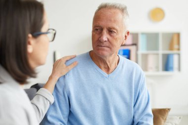 Klinikteki ya da ofisteki terapi seansında yaşlı bir adama danışan genç kadın psikologun portresi