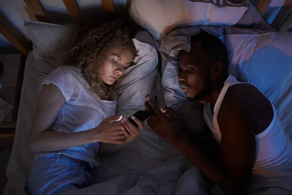 View Young Mixed Race Couple Lying Bed Night Using Smartphones — Stock Photo, Image
