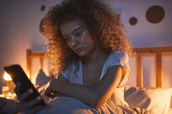 Портрет Кучерявого Молодої Жінки Сидить Зручному Ліжку Вночі Тримає Мобільний — стокове фото