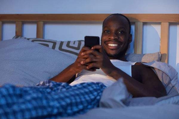 Portrait Smiling African American Man Using Smartphone Bed Night Looking — Stock Photo, Image