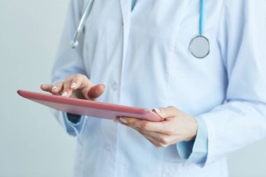 Klinikte çalışırken dijital tablet kullanan tanınmayan kadın doktorların orta bölüm görünümü, kopya alanı ile kapatın