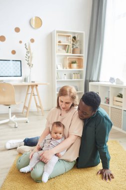 Modern ırklar arası ailenin dikey portresi evde oturmuş, tatlı melez bir bebekle oynarken, boşluğu kopyalıyor.