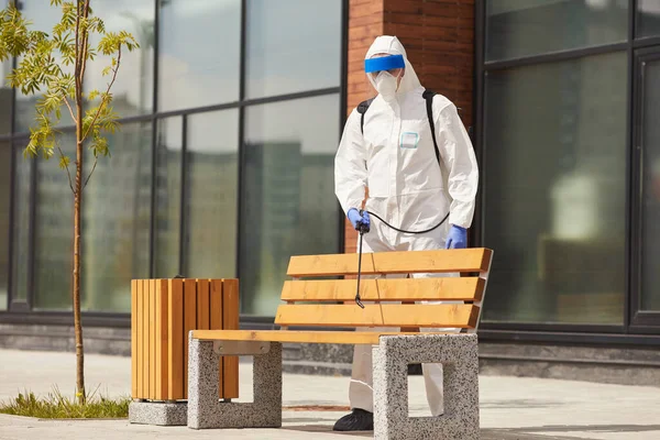工作台外消毒或清洁时 穿着防护服在长椅上喷洒化学品的工人全长肖像 复制空间 — 图库照片