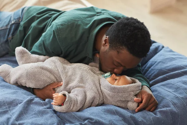 美しいですアフリカ系アメリカ人の父キス可愛いです赤ん坊ながらベッドの上に横たわっ居心地の良い家のインテリア コピースペース — ストック写真