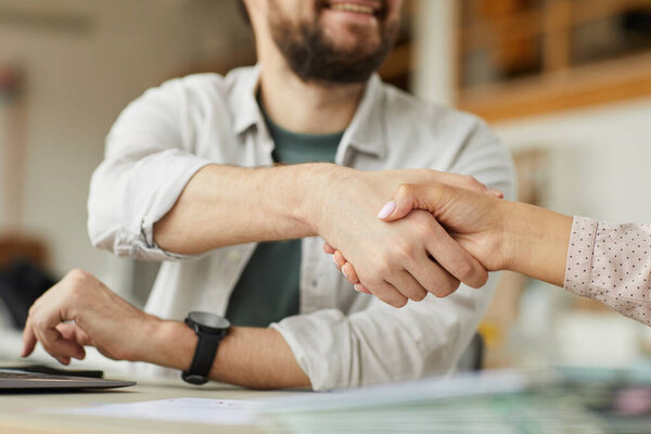 Крупный план улыбающегося бородатого мужчины пожимающего руку коллеге в минимальной офисной обстановке, копировальное пространство