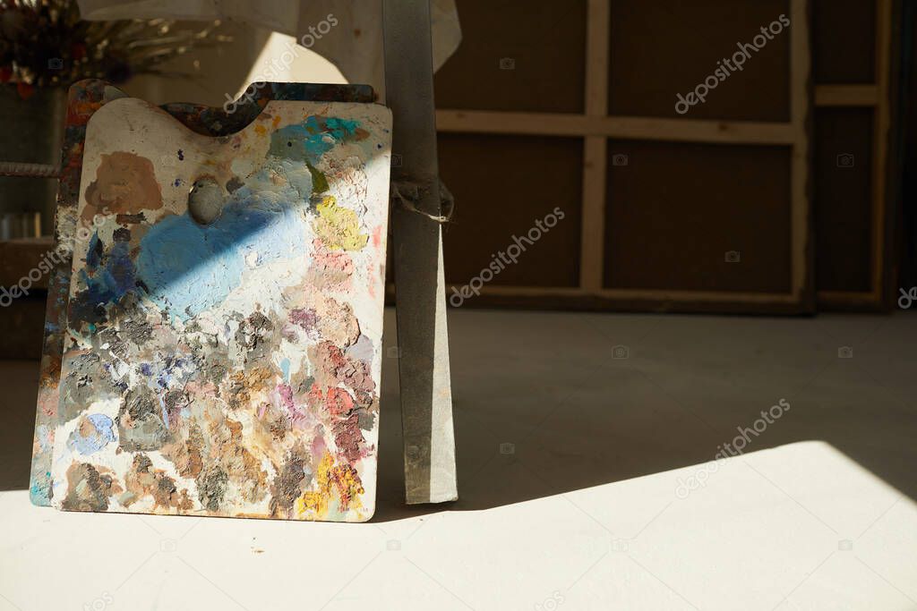 Background image of colorful artists palette lit by sunlight in empty art studio interior, copy space