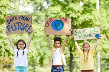 SAVE PLANET ile tabela tutan üç çocuğun belden yukarı portresi Doğayı protesto ederken geleceği koru, alanı kopyala