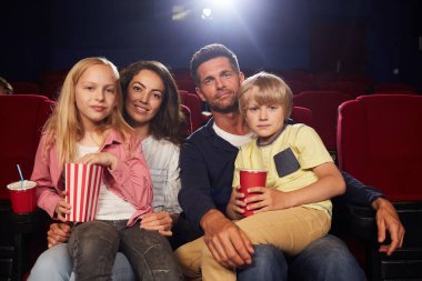 Sinemada film izlemek için bekleyen iki çocuklu mutlu aile portresi.