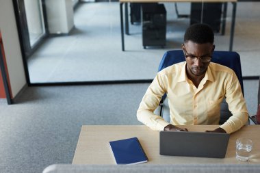 Modern ofiste çalışırken dizüstü bilgisayar kullanan zarif Afro-Amerikan işadamının en düşük açılı portresi, boşluğu kopyala