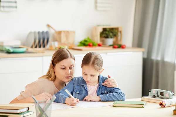 有爱心的母亲温暖的画像 帮助小女孩在舒适的家中做家庭作业或在餐桌边学习 复制空间 — 图库照片