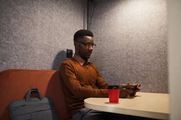 非洲裔年轻人独自坐在咖啡店时使用智能手机的肖像 复制空间 — 图库照片