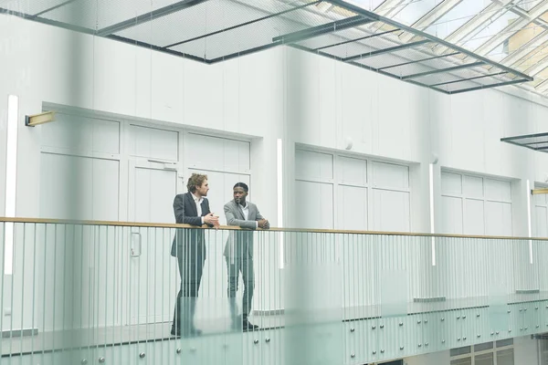 Широкий Угол Обзора Двух Успешных Бизнесменов Костюмах Стоящих Стеклянном Балконе — стоковое фото