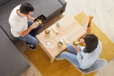 Ofiste ya da büyük kanepede oturup yemek yerken yemek yiyen kadın ve erkek portresinin üstünde, boşluğu kopyala