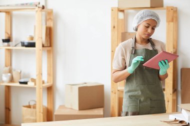 Yemek dağıtım servisinde çalışırken dijital tablet kullanan kadın işçinin belindeki portreyi kopyala