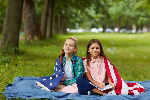 Parkta Piknik Battaniyesinde Oturan Kameraya Gülümseyen Amerikan Bayrağıyla Kaplı Iki — Stok fotoğraf