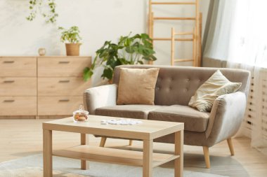 Rahat bej kanepe ve kahve masası, fotokopi masası içerisindeki rahat evin sıcak tonlu arkaplan görüntüsü.