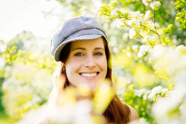 Young woman in beret in a white-flowering bush.