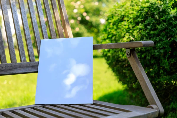 Mockup of a magazine cover on a wooden chair in the garden in summer.