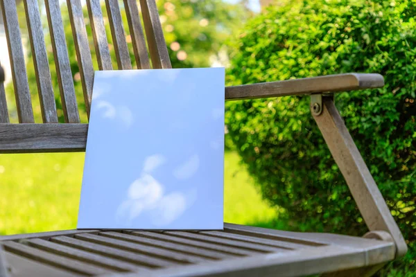 Mockup of a magazine cover on a wooden chair in the garden in summer.