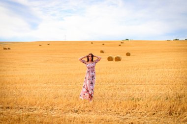 Kollarını sallayarak anız alanında Yaz elbiseli Genç kadın.