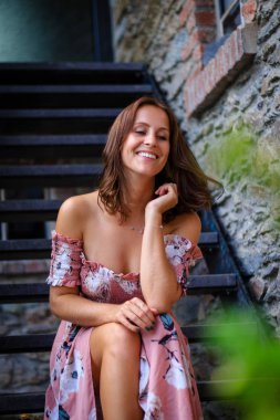 Yazlık elbise genç kadın bir çiftlik evi merdivenlerde oturuyor.