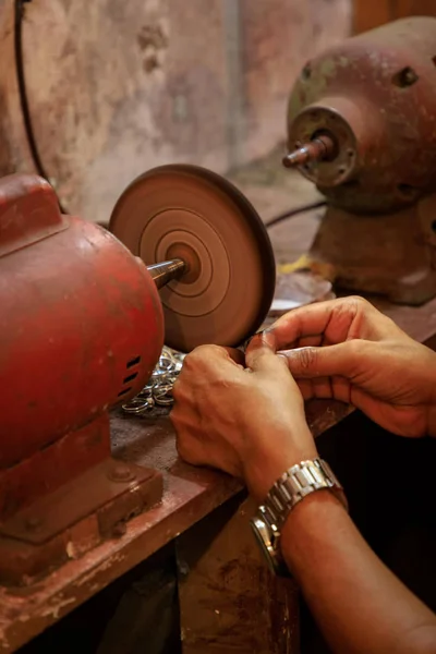 Jewelry smith polishes a lapis lazuli ring on a polishing machine in a backyard workshop in Puerto Plata, Dominican Republic.