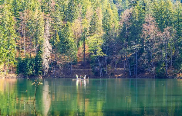 Raft with people on lake in the background of high mountains and green forest, concept of traveling in the wild, copy space, — Stock Photo, Image