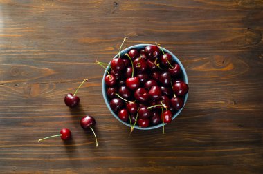 Kiraz seramik mavi kase ahşap arka plan, tatlı yaz gıda, meyve kavramı. Yat, uzay, closeup Kopyala