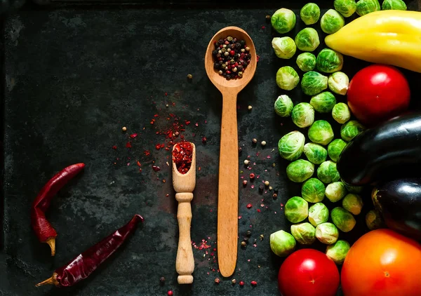 wooden spoon with spices and fresh vegetables for healthy cooking on background of old rusty metals, top view,copy space, closeup. Diet, pure food or the concept of vegetarian food.
