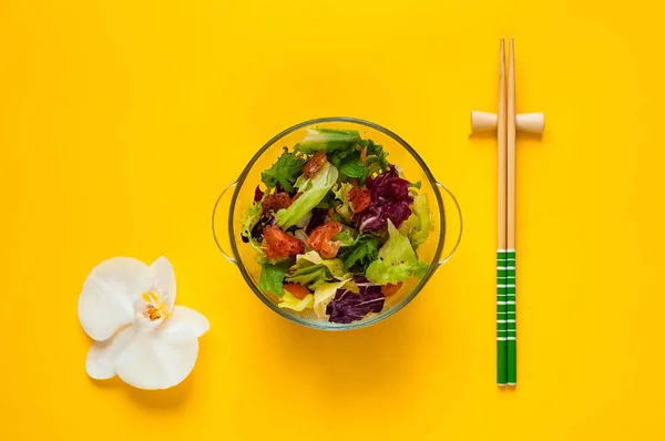 Lachssalat auf gelbem Hintergrund mit Orchidee. hausgemachtes Essen. das Konzept der gesunden Ernährung, Kopierraum, Nahaufnahme. — Stockfoto