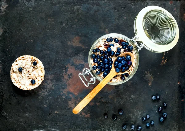 Yulaf ezmesi meyve ve fındık, sağlıklı kahvaltı malzemeler. Yaban mersini ve ahududu vintage paslı metal arka plan, organik gıda kavramı, kopya alanı, açık cam kavanoza ev yapımı granola portre