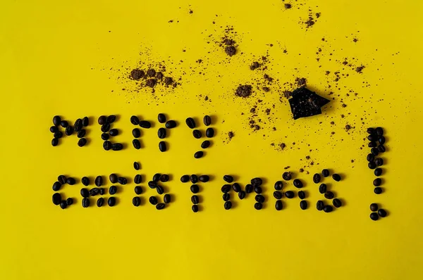 Inscription of merry Christmas, laid out from the  beans of coffee. Creative Chocolate background with on yellow texture-color of the year 2019,closeup, copy space — Stock Photo, Image