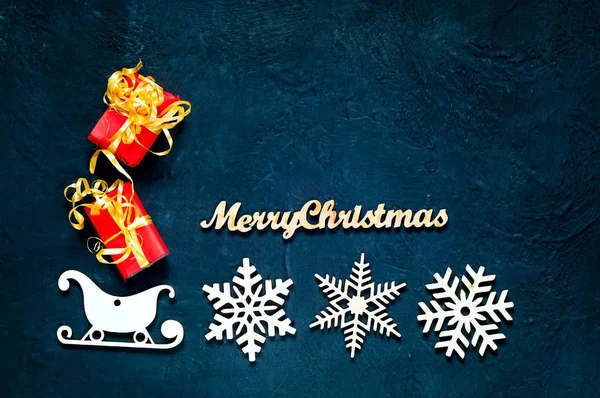 Flocs de neige et traîneaux de Noël en bois décoratifs.Fond bleu foncé vacances avec boîtes cadeaux de Noël, vue du dessus. . — Photo