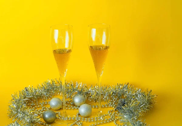 Λαμπρή Χριστουγεννιάτικη διακόσμηση. Γεμάτο γυαλιά και μπουκάλι σαμπάνιας διακοσμημένα με εορταστικό θέμα σε κίτρινο φόντο, η έννοια της Πρωτοχρονιά, στενή-up, αντίγραφο χώρου — Φωτογραφία Αρχείου