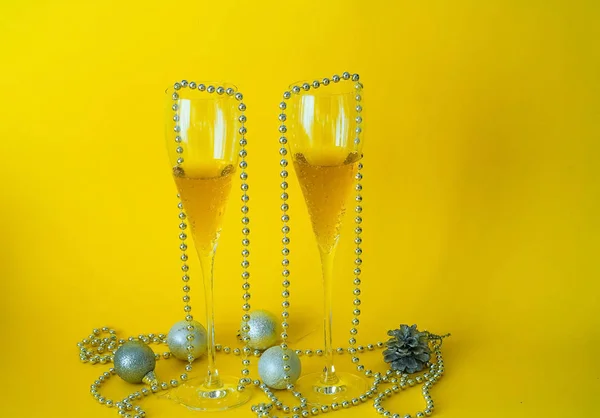 Decoração de Natal brilhante. Copos cheios e garrafa de champanhe decorados em tema festivo no fundo amarelo, conceito de feriado de Ano Novo, close-up, espaço de cópia — Fotografia de Stock