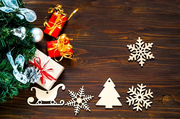 Διακοσμητικά ξύλινα Χριστούγεννα νιφάδες χιονιού και έλκηθρα. Διακοπές ξύλινο υπόβαθρο με κουτιά δώρου Χριστουγέννων και ελάτης, το top view. — Φωτογραφία Αρχείου