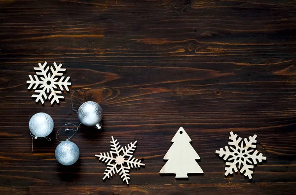 Decoración de Navidad y Año Nuevo. Copos de nieve de madera decorativos y bolas de plata sobre fondo de madera, concepto de vacaciones de Año Nuevo, primer plano, espacio para copiar —  Fotos de Stock