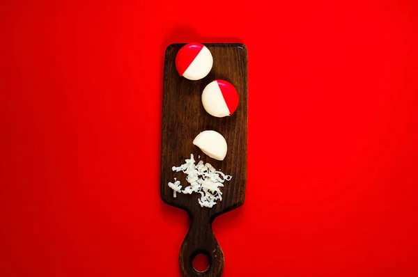 Kleiner runder Käse in Paraffinverpackung auf Holzbrett auf rotem Hintergrund, Draufsicht, Kopierraum — Stockfoto