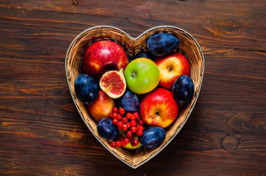 Elma, Erik ve incir saman vazoda ahşap arka plan, üstten görünüm, organik gıda kavramı, diyet, üzerinde kalp şeklinde yapılan gıda veya vejetaryen kavramı detoks. Düz yatıyordu. Kopya alanı. 