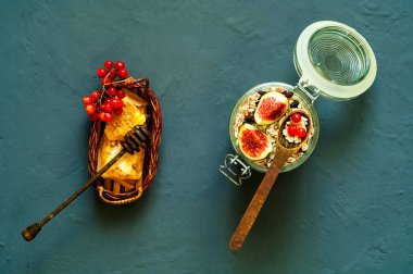 Renkli kahvaltı. Peteğin ve yulaf ezmesi beton koyu arka plan üzerinde cam kavanoza incir ile tatlım. Sağlıklı beslenme kavramı, portre, kopya alanı, ana sayfa görünümü