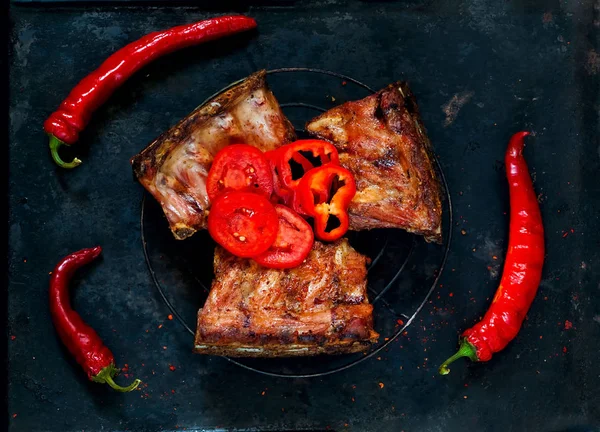 Gli Originali Costolette alla griglia con peperoncino piccante e pomodori su fondo scuro.Le costolette più pregiate, riccamente condite con spezie selezionate. Vista dall'alto, spazio di copia, disposizione piatta . — Foto Stock