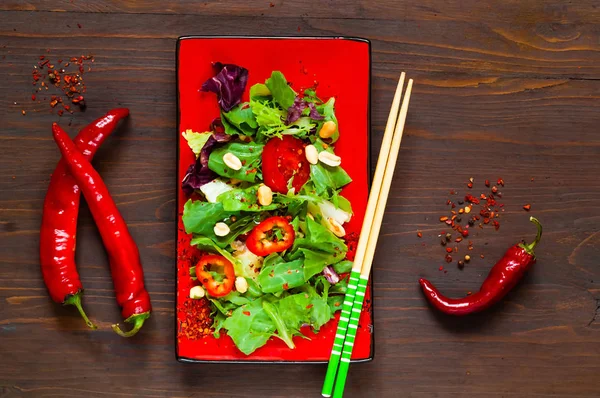 Lachssalat auf rotem Teller mit Stäbchen auf hölzernem Hintergrund, Bio-Food-Konzept, Detox-Food oder vegetarisches Konzept. — Stockfoto